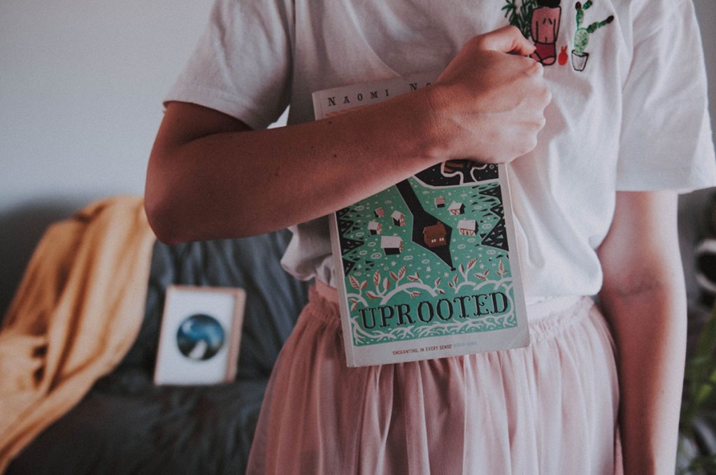 One girl holding a book, Uprooted by Naomi Novik.