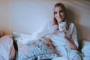 Girl on bed holding a fox mug.
