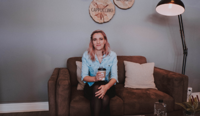 Girl sitting on couch, with coffee in hand.
